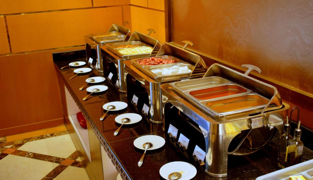 a row of buffet tables with dishes and spoons at Emirates Stars Hotel Apartments Dubai in Dubai