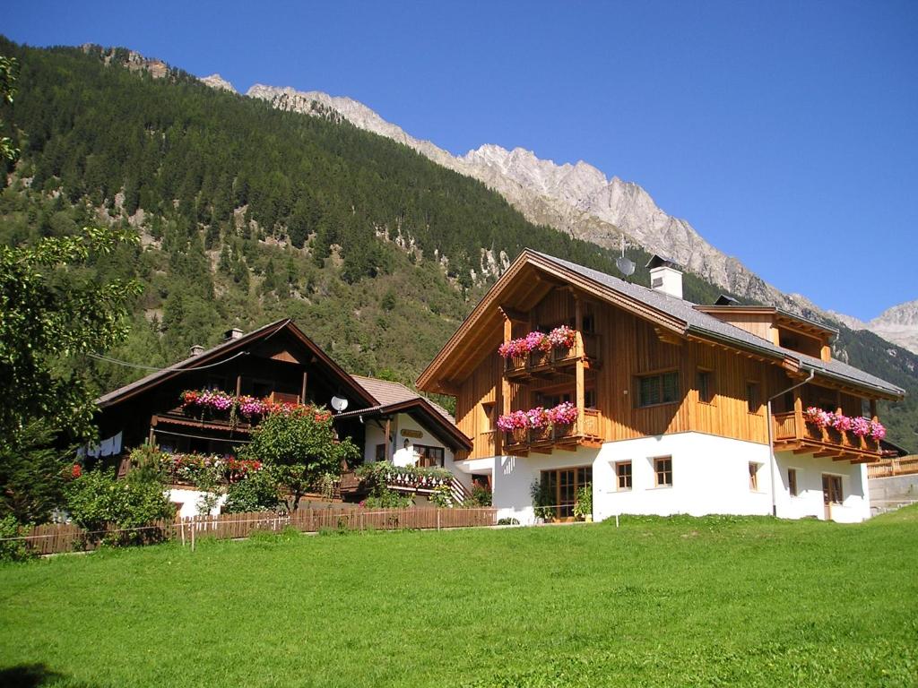 a house with flowers on the balconies in a field at Müllerhof in Anterselva di Mezzo
