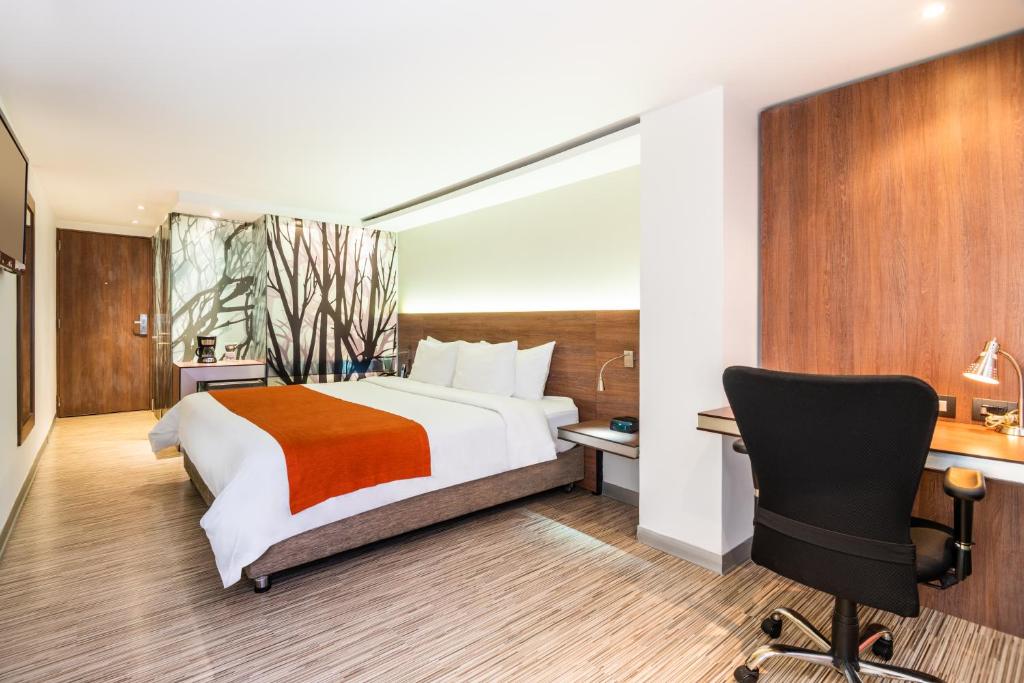 Schlafzimmer mit einem Bett, einem Schreibtisch und einem Stuhl in der Unterkunft SHG Bogotá 100 Design Hotel in Bogotá