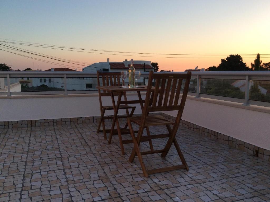a table and chairs on a balcony with the sunset at Casa Das Ondas - Praia Do Norte in Nazaré
