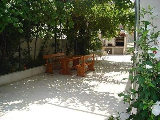 a wooden bench sitting under a tree on a patio at Villa Tajnikov in Hvar