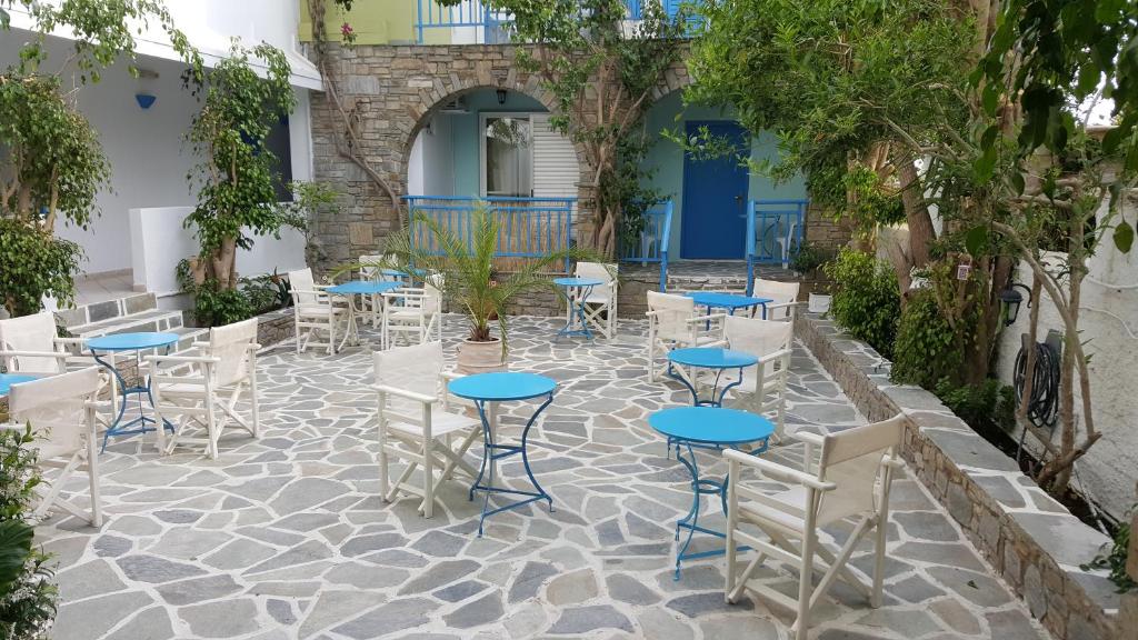 um pátio com mesas, cadeiras e árvores em Aratos Hotel em Parikia