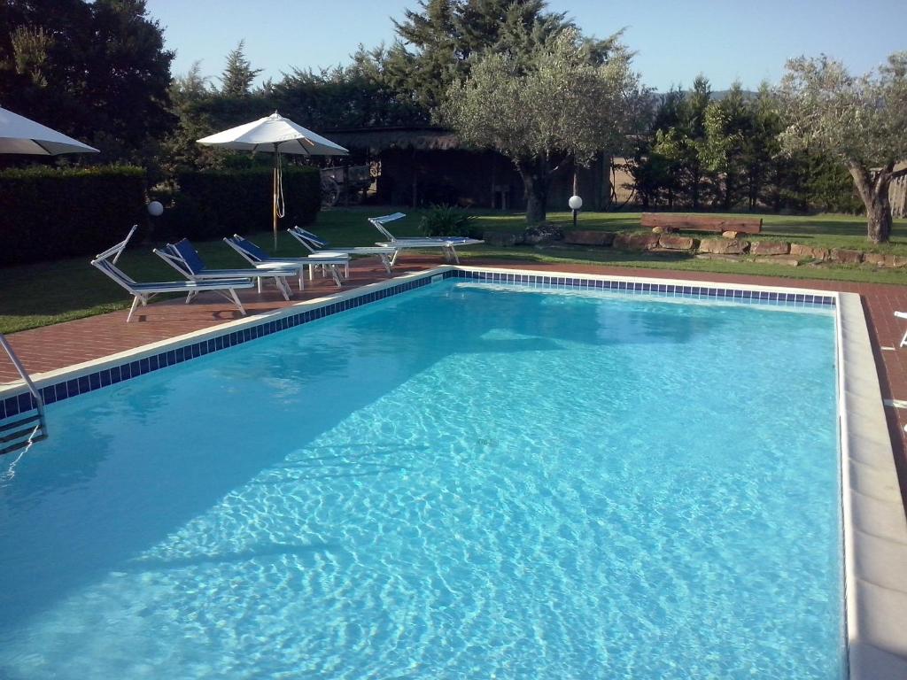 una gran piscina con 2 sillas y una sombrilla en Agriturismo Campotondello, en Gavorrano