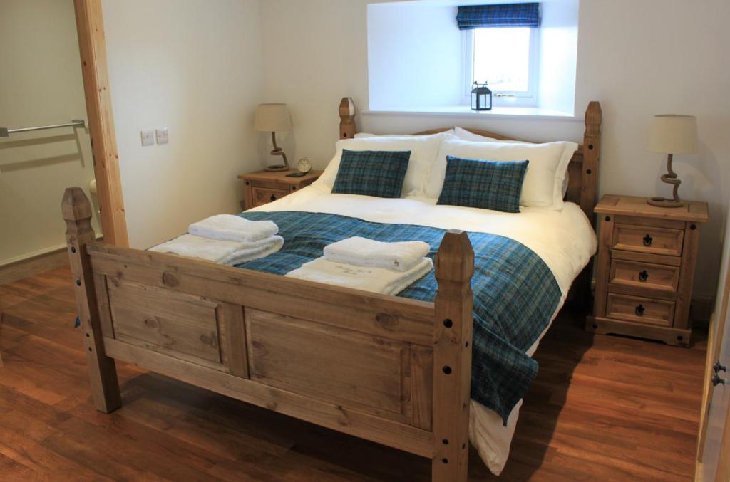 a bedroom with a large wooden bed with towels on it at The Annex at Borlum House in Reay