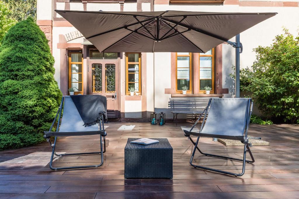 2 stoelen en een parasol op een patio bij Chambre d'hôtes Du côté des remparts in Wissembourg