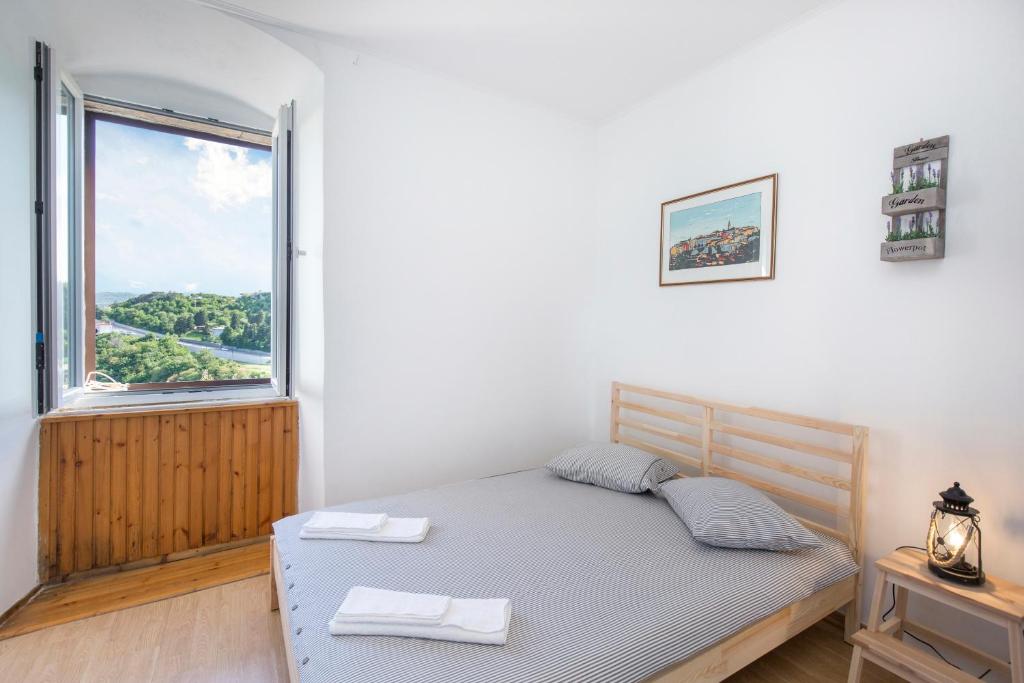 ein Schlafzimmer mit einem Bett und einem großen Fenster in der Unterkunft Studio Apartman Vedran in Labin