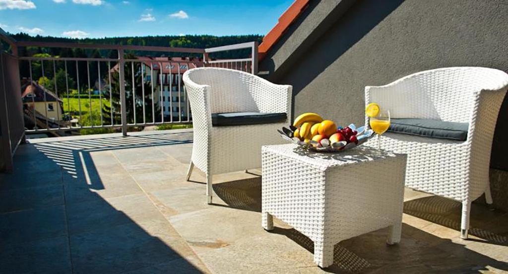 two chairs and a bowl of fruit on a table on a balcony at Apartamenty Polanica MyWeek in Polanica-Zdrój