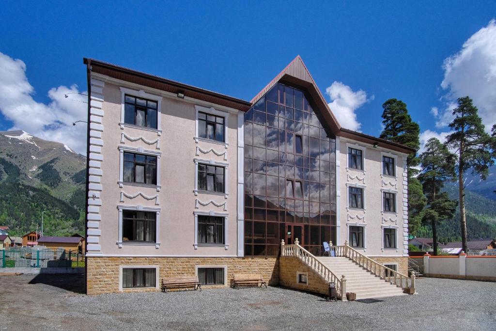 a large white building with a staircase in front of it at Hotel Kavkaz in Arkhyz