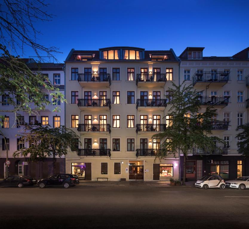 un gran edificio blanco con coches estacionados frente a él en Luxoise Apartments, en Berlín