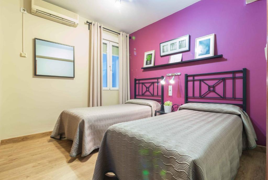 2 camas en una habitación con una pared púrpura en Hostal Jentoft, en Sevilla