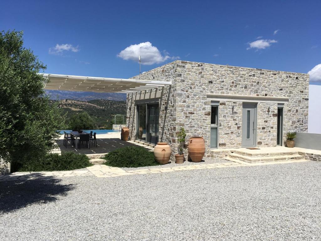 a stone house with a patio and a pool at Villa Lemoni in Kamilari