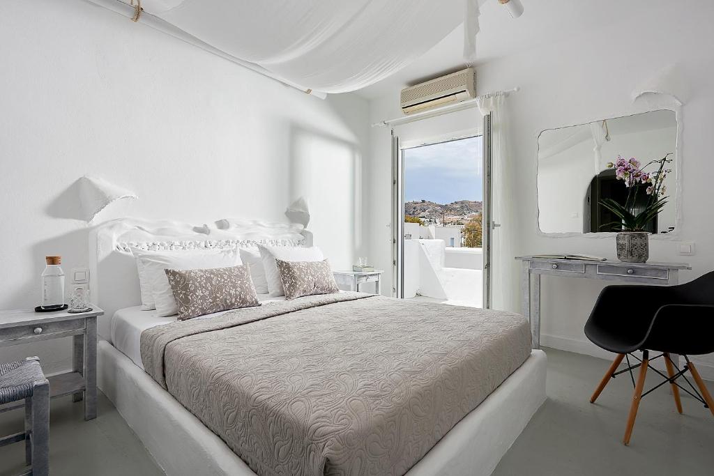 een witte slaapkamer met een bed en een spiegel bij Milos Hotel in Adamas