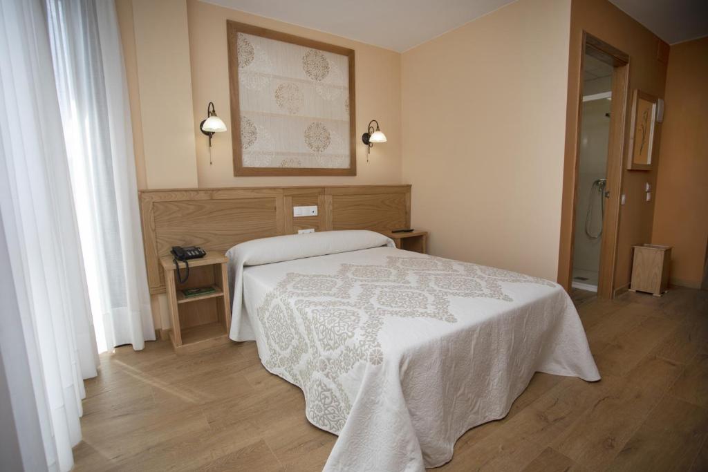 a bedroom with a bed with a white blanket at Hotel Novoa in Sarria