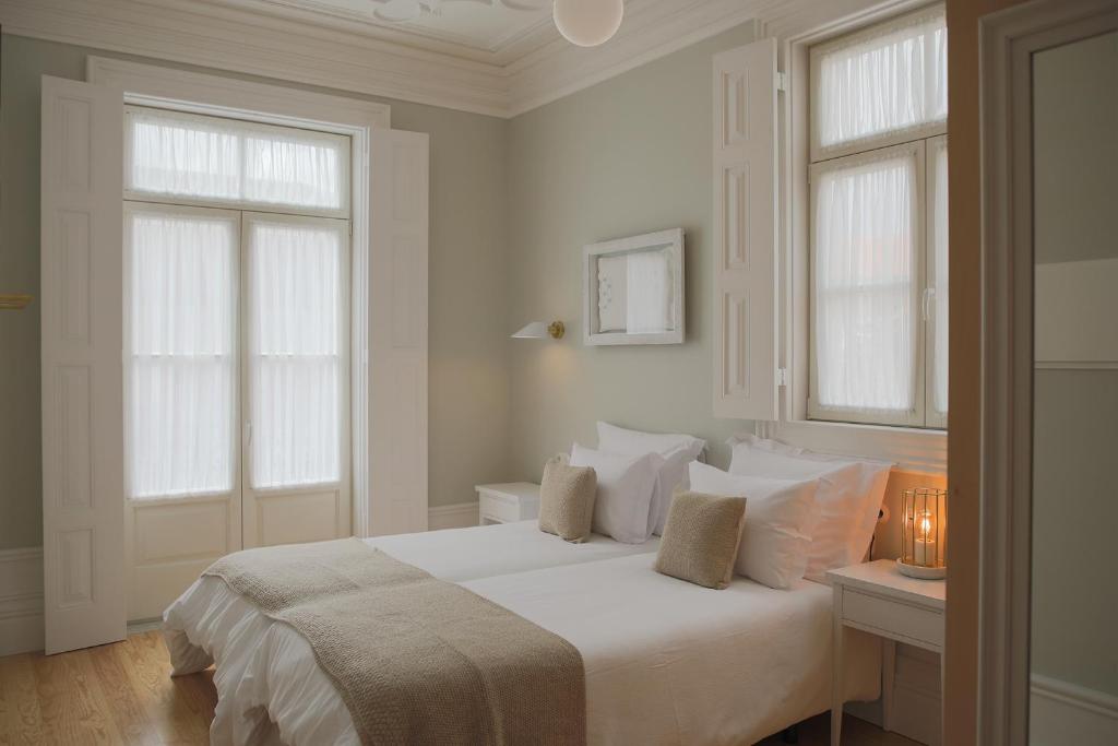 a white bedroom with a bed and two windows at Original Douro Hotel in Peso da Régua