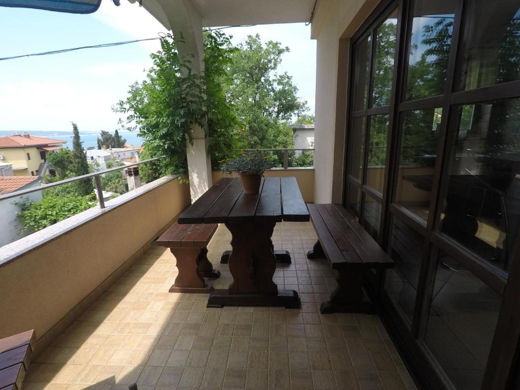uma varanda com uma mesa de madeira e um banco. em Apartman Štefanija em Selce