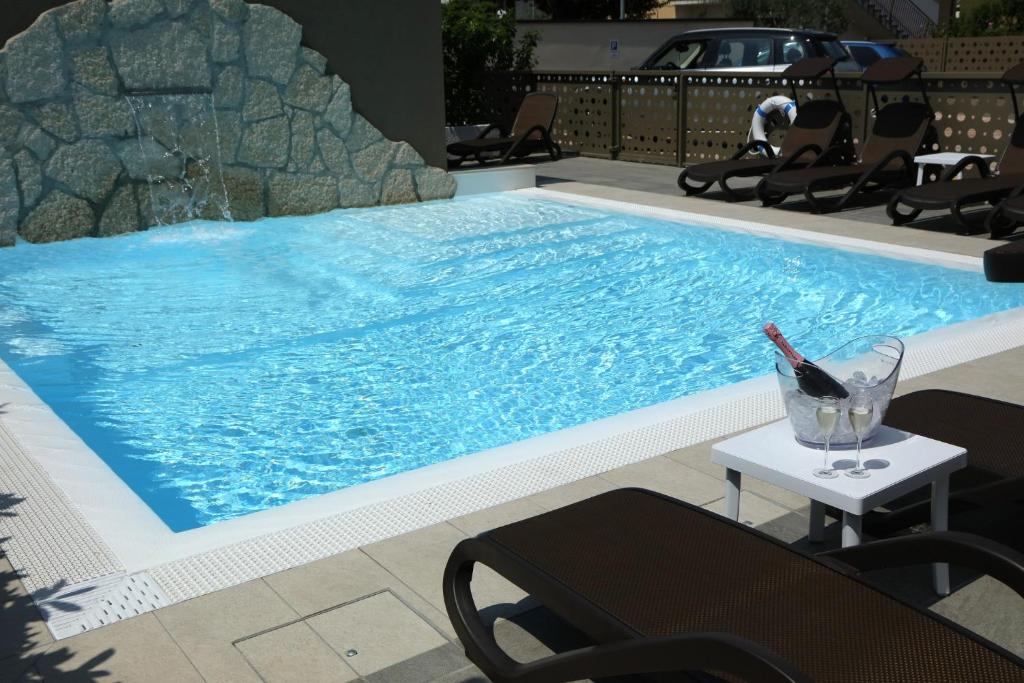a large swimming pool with a drink on a table at Hotel Buena Onda in Peschiera del Garda