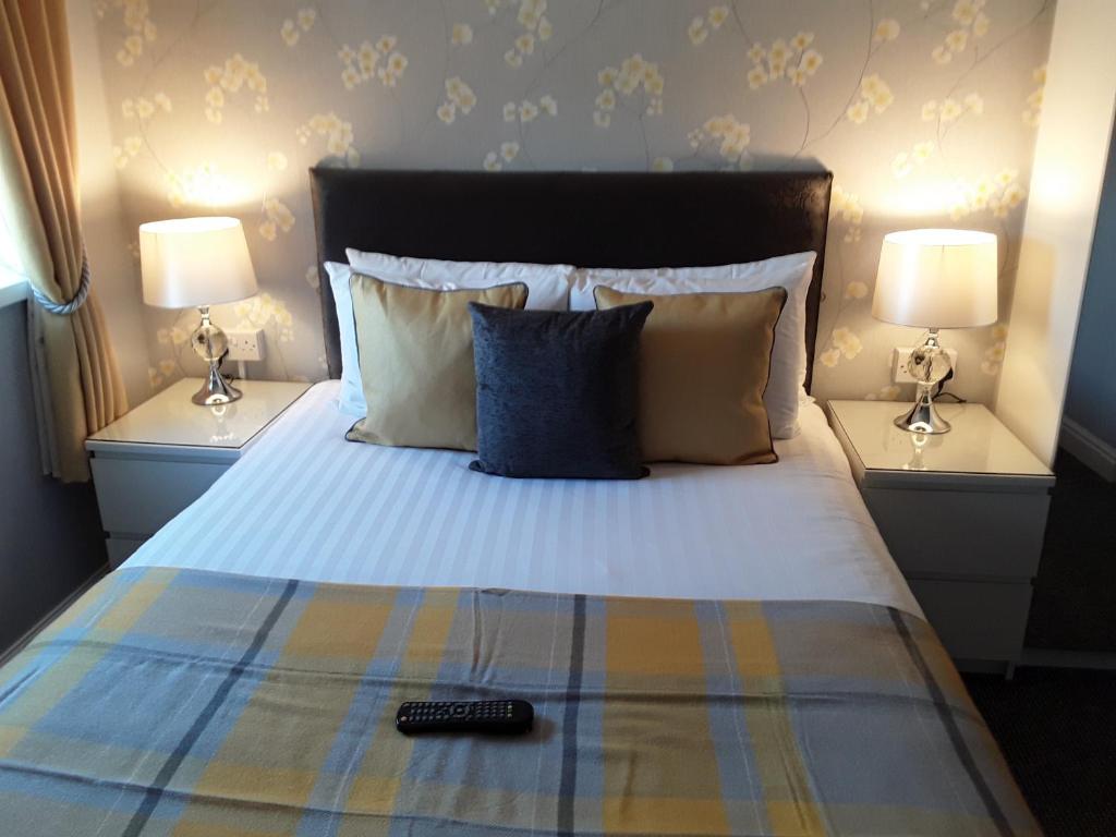 a bed with two lamps and a remote control on it at Manchester House in Blackpool