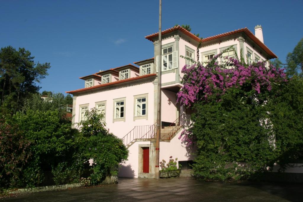 una casa blanca con flores púrpuras delante de ella en Quinta da Picaria, en Santo Tirso