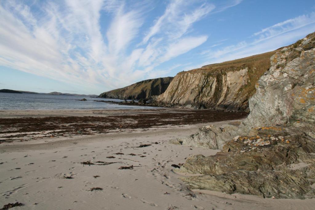 a beach with rocks and the ocean and a blue sky at Tamara Apartment in Sandwick