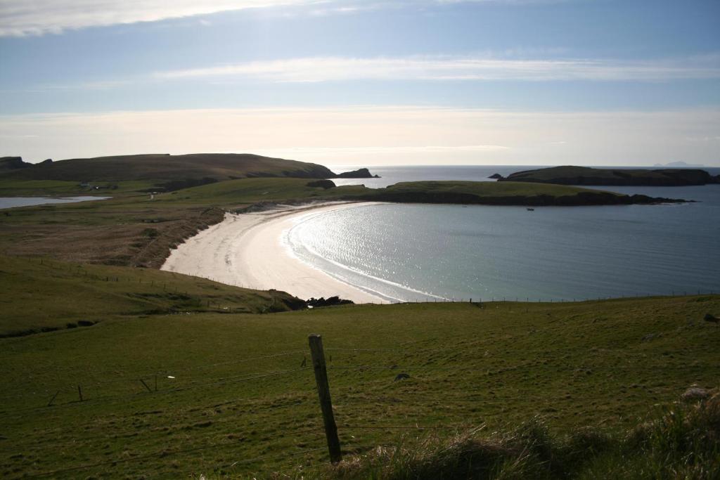 a beach in the middle of a field with the ocean at Tamara Apartment in Sandwick