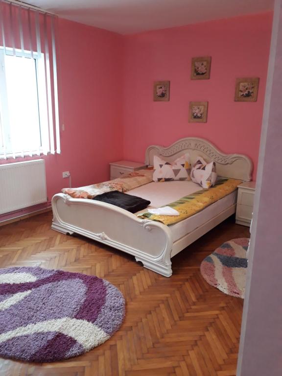a bedroom with a bed with pink walls and a rug at Casa Ade in Călimăneşti