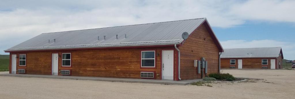 a large wooden barn with a metal roof at Howard's Motel in Glendo