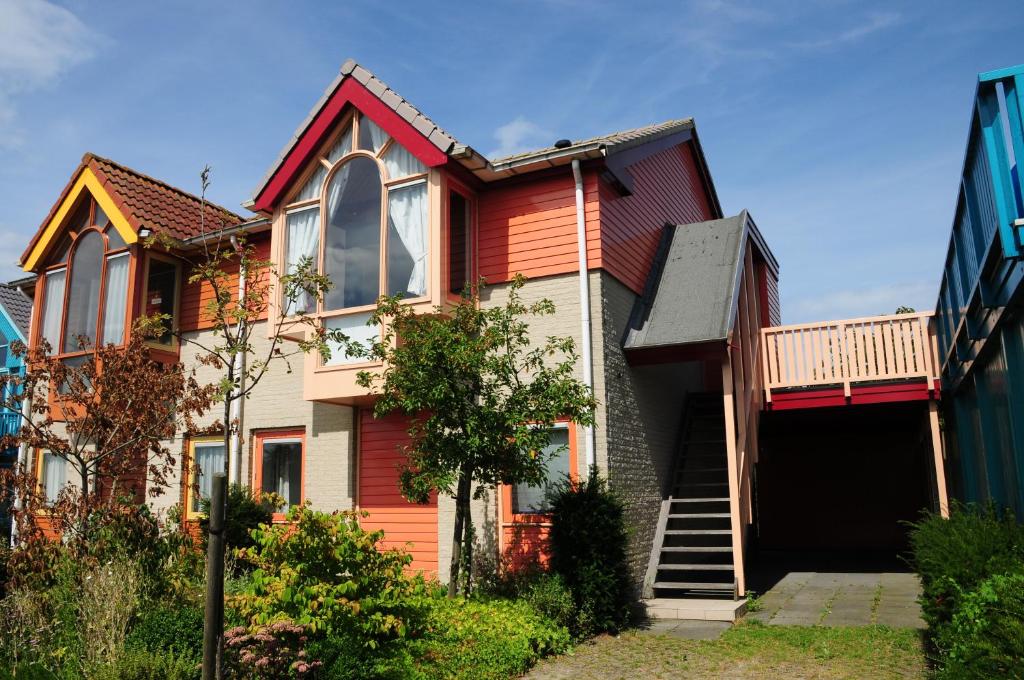 een huis met een rode deur en een balkon bij Grimaud 177 - Kustpark Village Scaldia in Hoofdplaat