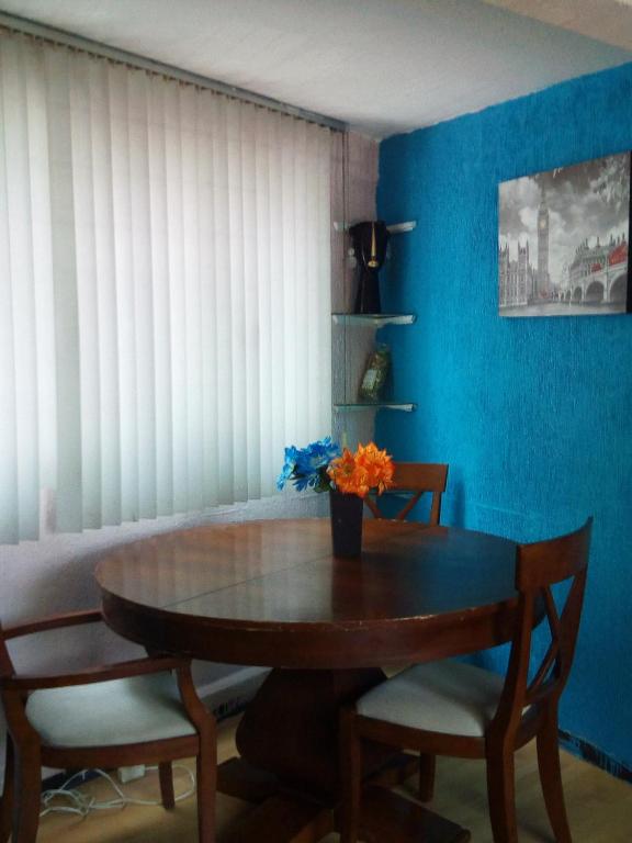 mesa de comedor con sillas y pared azul en Departamento de huéspedes Grijalva, en Ciudad de México