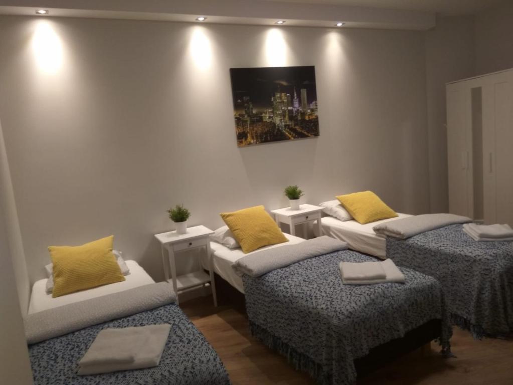 ワルシャワにあるKlopot 4 Apartmentの黄色い枕が付くベッド3台が備わる部屋