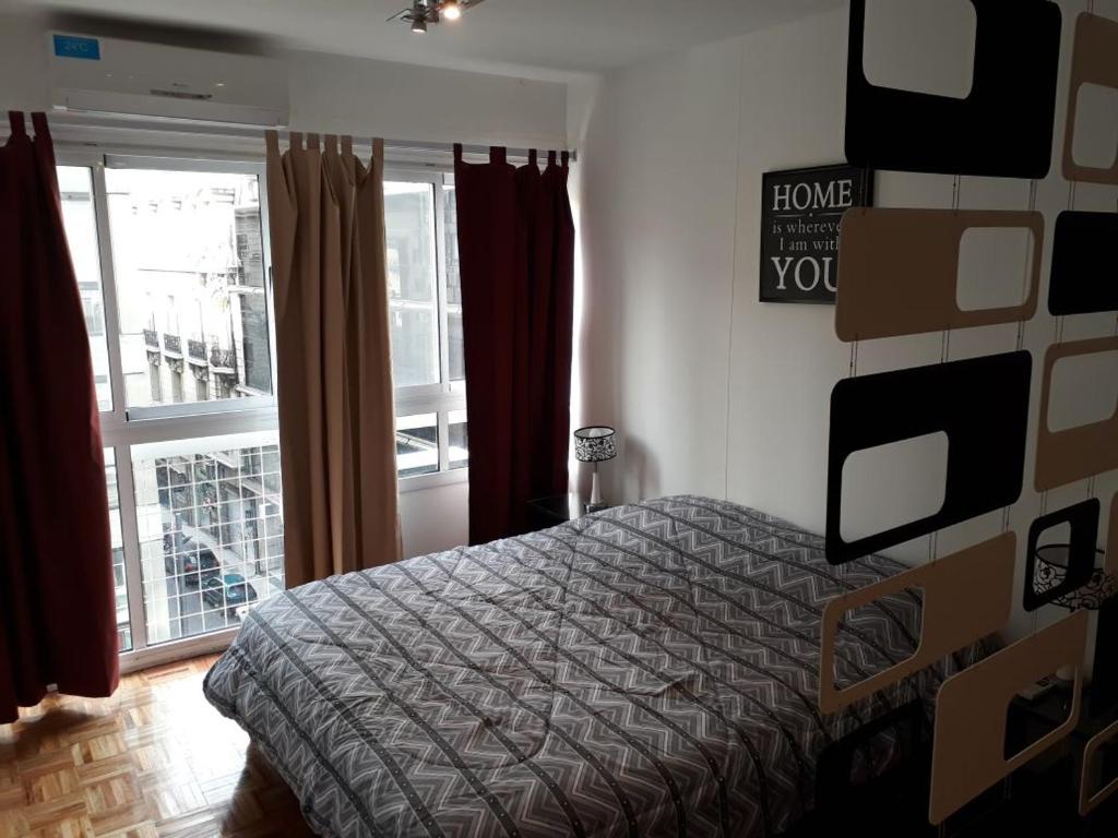 um quarto com uma cama e uma janela em Downtown Viamonte Apartment em Buenos Aires