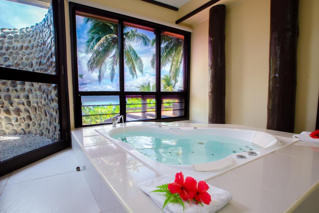 een badkamer met een bad en uitzicht op palmbomen bij Mana Island Resort & Spa - Fiji in Mana Island