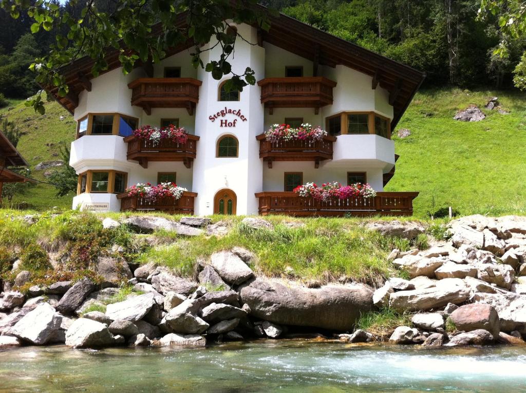 un bâtiment sur une colline à côté d'une rivière dans l'établissement Steglacher Hof, à Mayrhofen