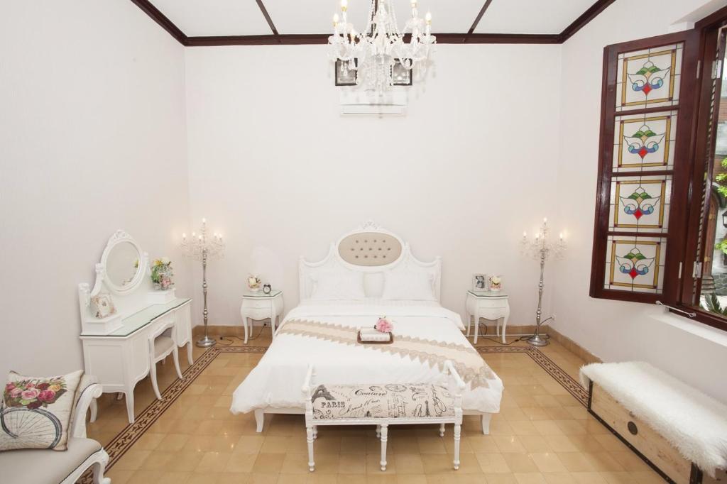 una camera con letto bianco e lampadario pendente di Huis Van Gustafine Floor 1 a Malang