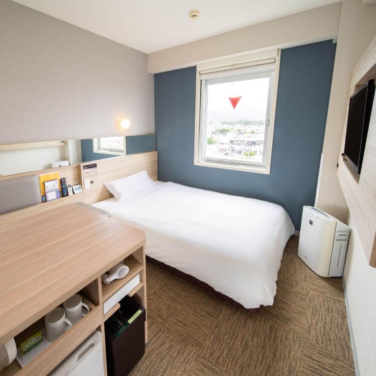 Un dormitorio con una gran cama blanca y una ventana en Super Hotel Okinawa Nago en Nago