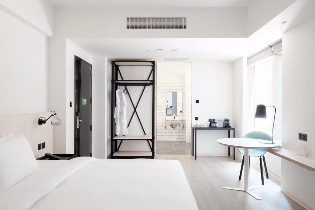 a white bedroom with a bed and a desk and a chair at amba Taipei Songshan in Taipei