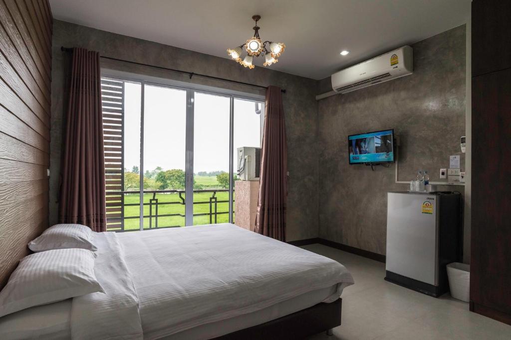 sypialnia z łóżkiem, lodówką i oknem w obiekcie Nava Resort w mieście Nakhon Nayok
