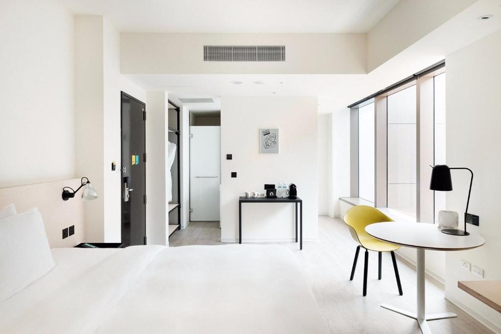a white living room with a table and yellow chairs at amba Taipei Songshan in Taipei