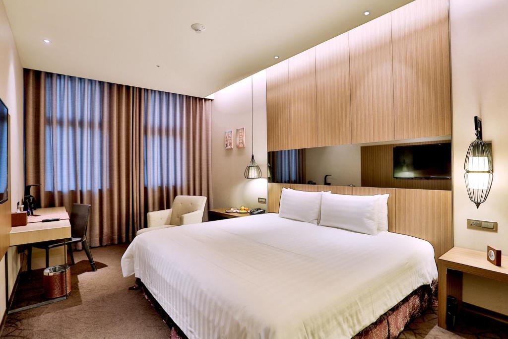 a hotel room with a large white bed and a desk at Hotel Intrendy in Taishan