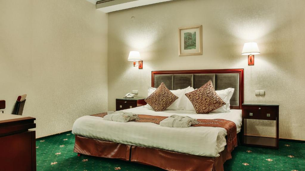 ein Hotelzimmer mit einem großen Bett mit Kissen in der Unterkunft Goldman Empire in Astana
