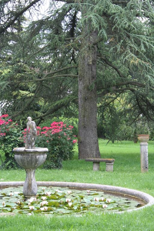 una fontana in un parco con un albero e una panchina di B&B Villa al Parco a Sala Baganza