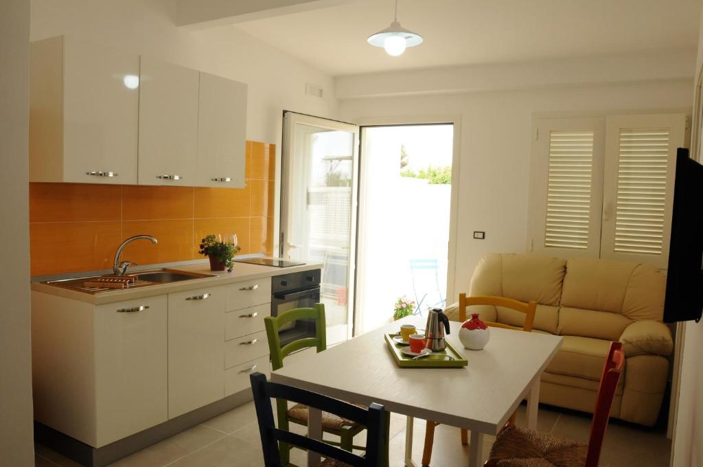 een keuken en woonkamer met een tafel en een bank bij Punta Prosciutto GMA Tourism in Porto Cesareo