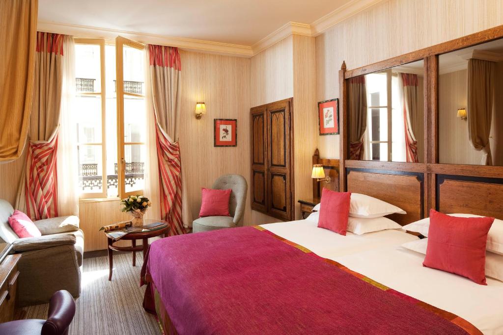 a hotel room with a large bed and a chair at Au Manoir Saint Germain in Paris