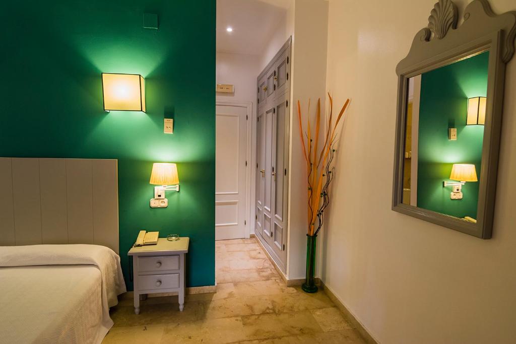 ein Schlafzimmer mit grünen Wänden, einem Bett und einem Spiegel in der Unterkunft Hostal Drago in Pueblo Nuevo de Guadiaro