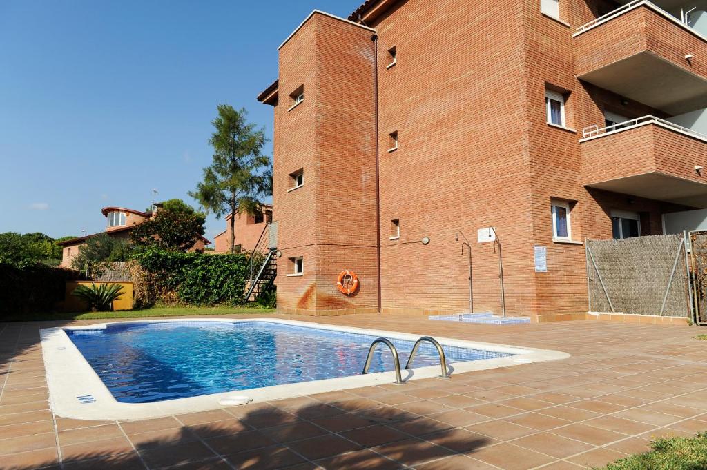 a swimming pool in front of a brick building at Aparthotel Marsol in Castelldefels