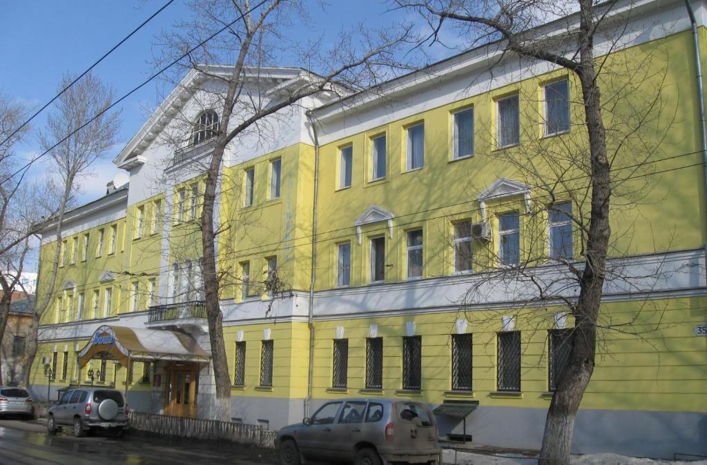 薩馬拉的住宿－沃爾納酒店，一座黄色的建筑,前面有汽车停放