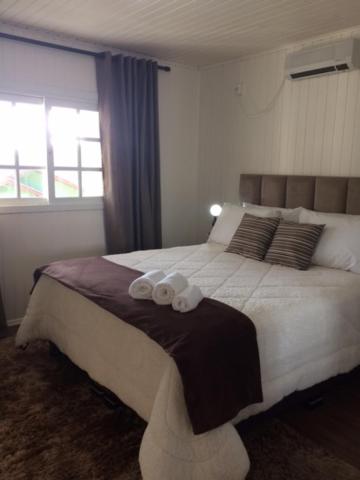 um quarto com uma cama grande com duas toalhas em Chalé Vale do Floresta em Gramado