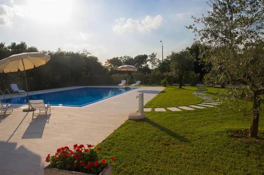 podwórko z basenem i parasolem w obiekcie Agriturismo Dell'Orto Apartments w Weronie