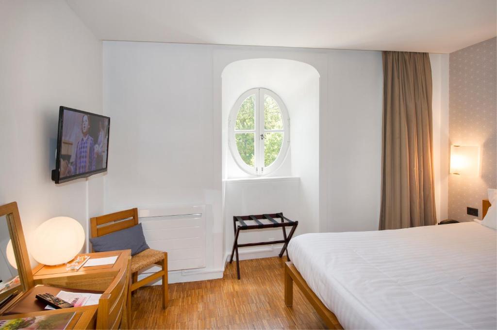 a hotel room with a bed and a desk and a window at Domaine De Barres in Langogne