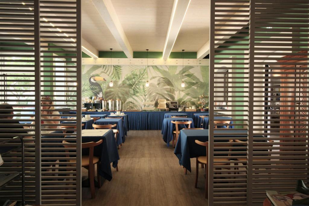 a dining room with tables and chairs and a mural at Hotel Lucerna in Castiglione della Pescaia