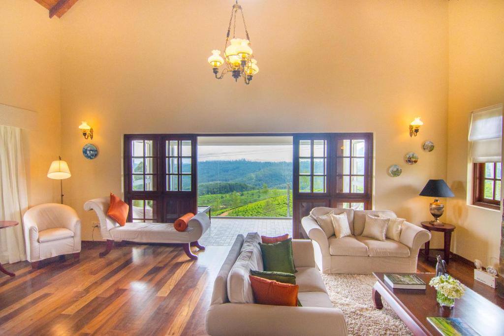 a living room filled with furniture and a large window at The Glenmor Bungalow 3 Bedroom Scenic Retreat, Nuwara Eliya in Nuwara Eliya